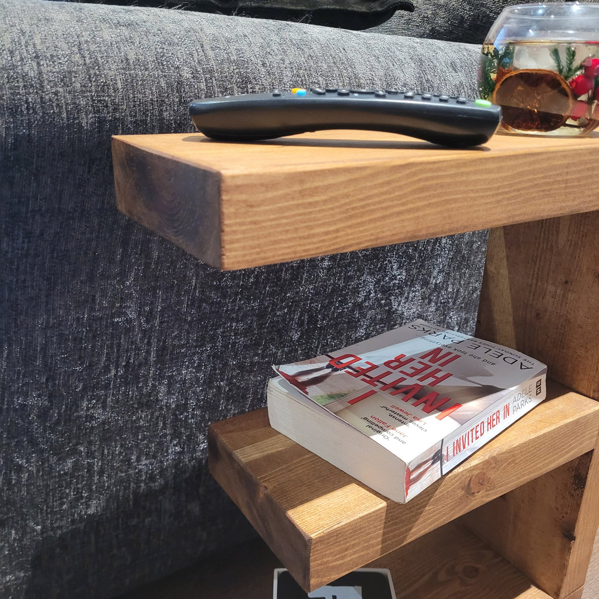 Close view of the E-shaped table top with a remote control, and a book on the middle shelf