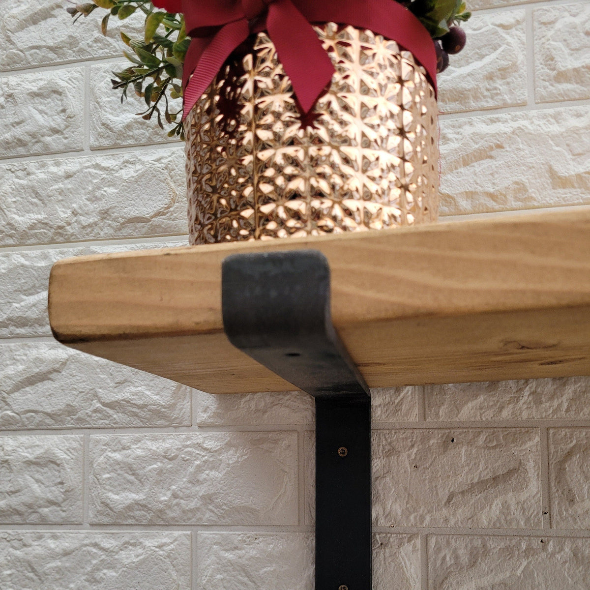 Underside view showing the black lipped metal bracket supporting the solid wood shelf