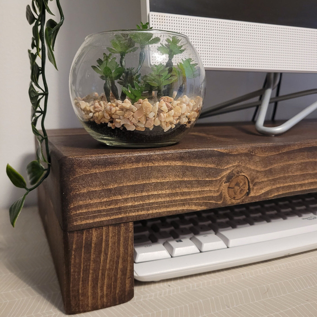 Low angle showing the solid pine leg of the monitor stand and the keyboard slid under it